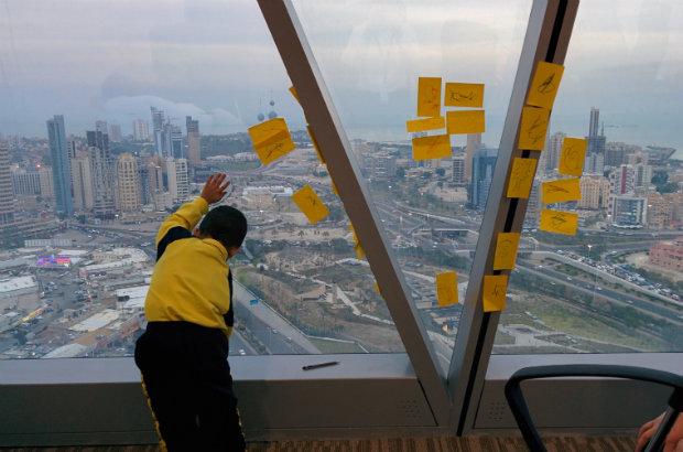 A child leaning against the window of a skyscraper, looking out at across the city