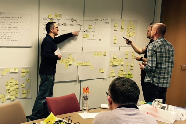 Image of the design sprint in progress - team members at a wall with post its