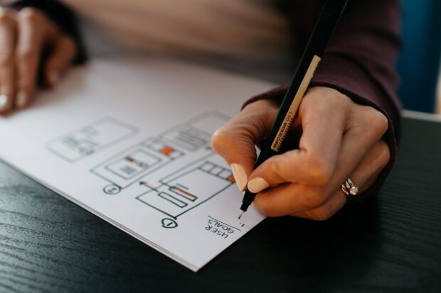 An image of a person's hands drawing a user design map.
