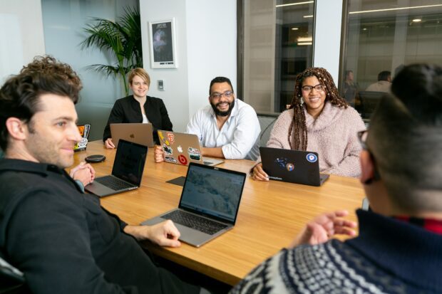 An image of tech apprentices sitting together at a table with laptops open