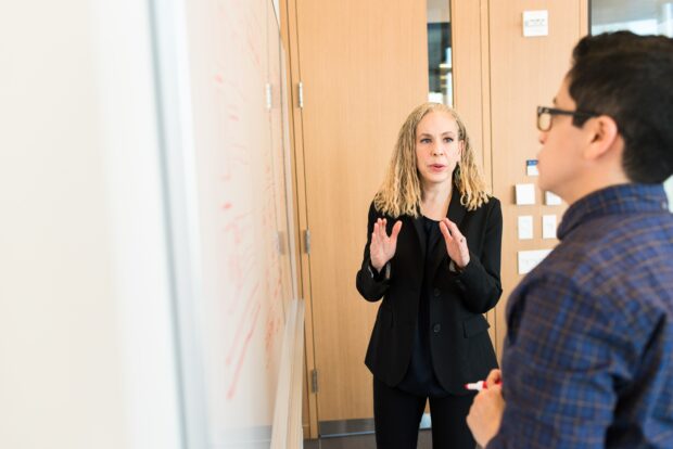 An image of two colleagues in front of a whiteboard having a discussion