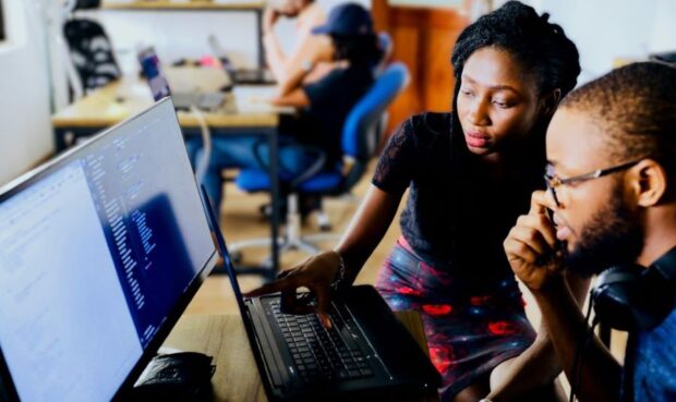 An image of a group of graduates sitting around a computer